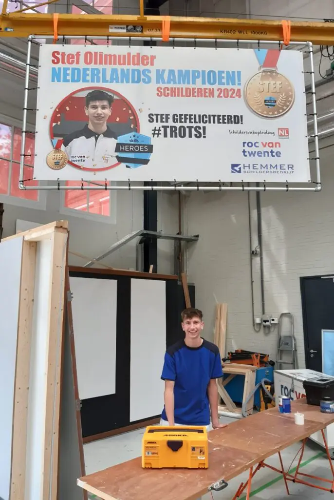 Stef onder een groot spandoek