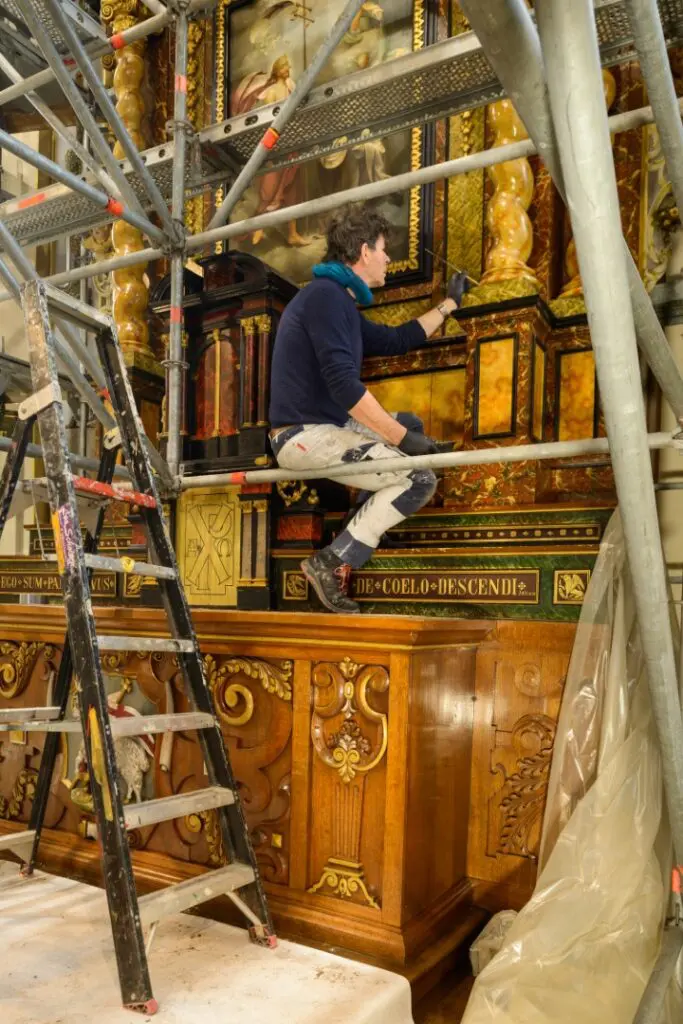Leo Scholten (in 2022) bezig met het retoucheren van het altaar in de kapel van de zusters Birgittinessen te Uden. Foto Willem Kuijpers